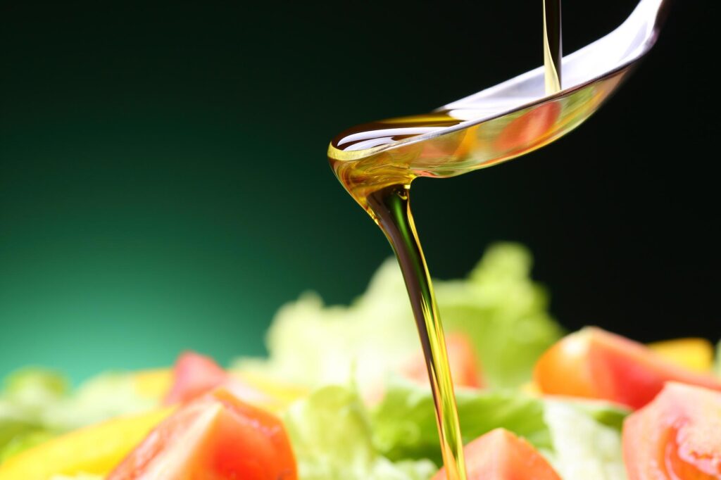 野菜に回しかけるオリーブオイルとスプーン