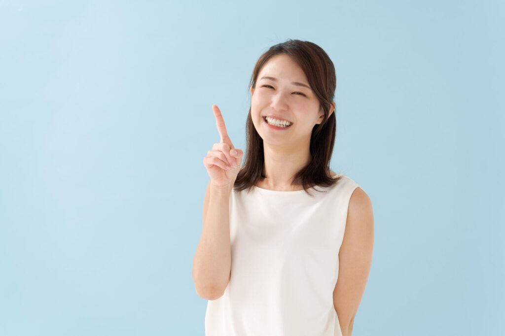 人さし指を立ててほほ笑む女性