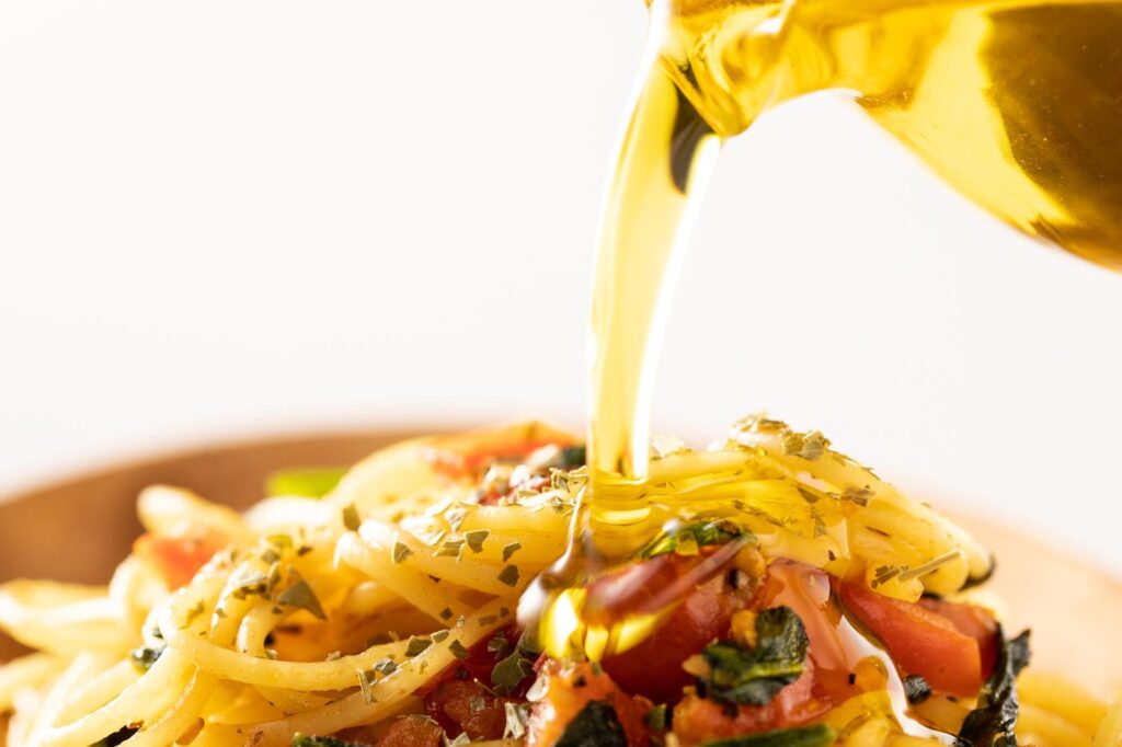 パスタにオリーブオイルをかける様子