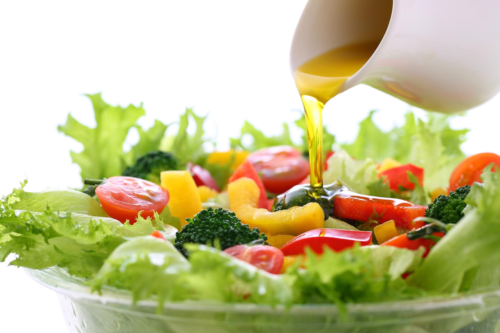 オリーブオイルをサラダにかける様子