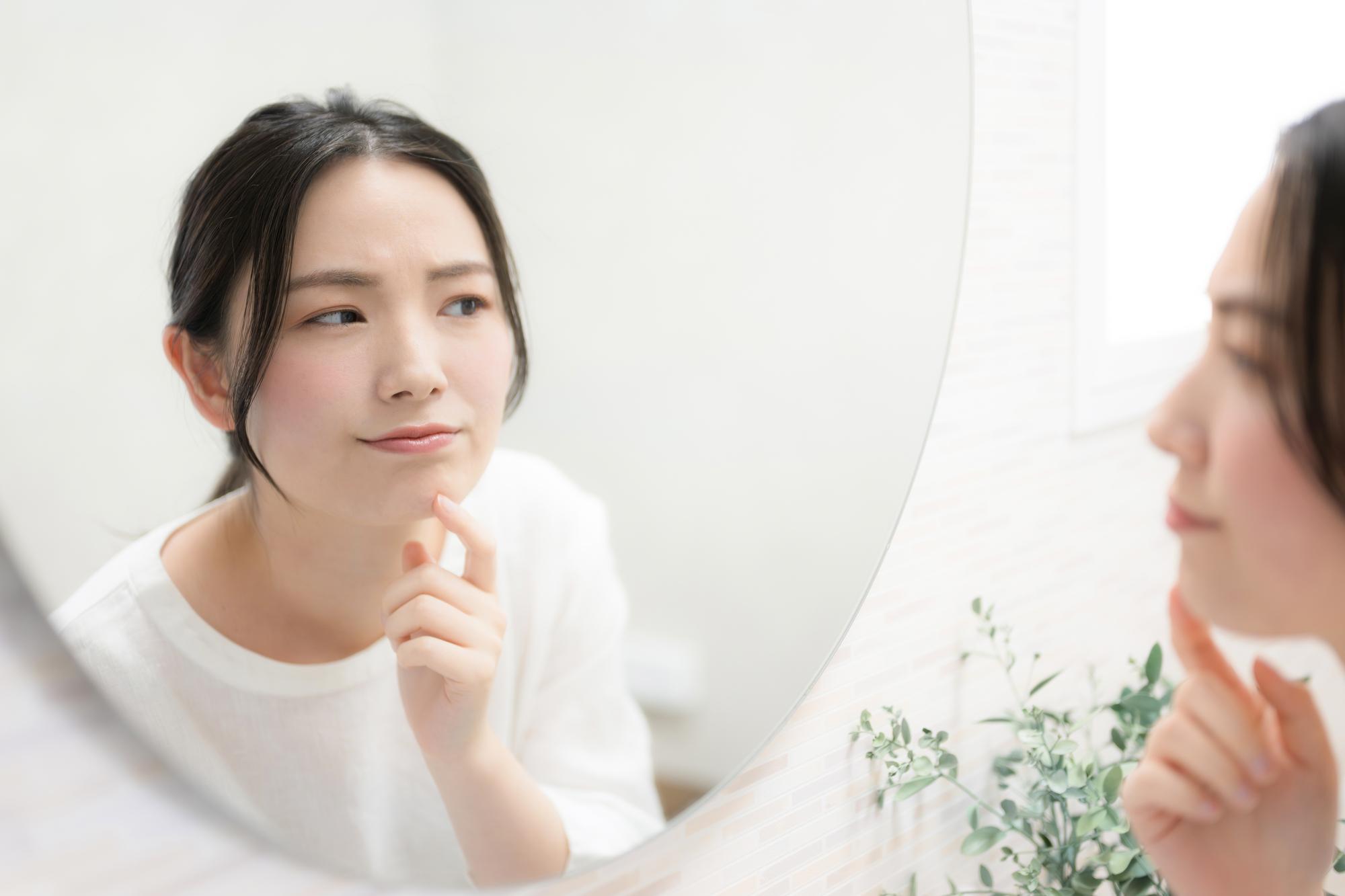 鏡を見て肌の様子を伺う女性