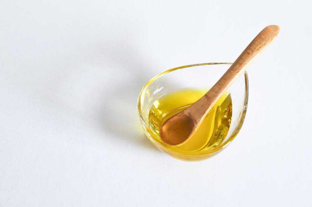ガラス容器に入れたオリーブオイルと木製スプーン