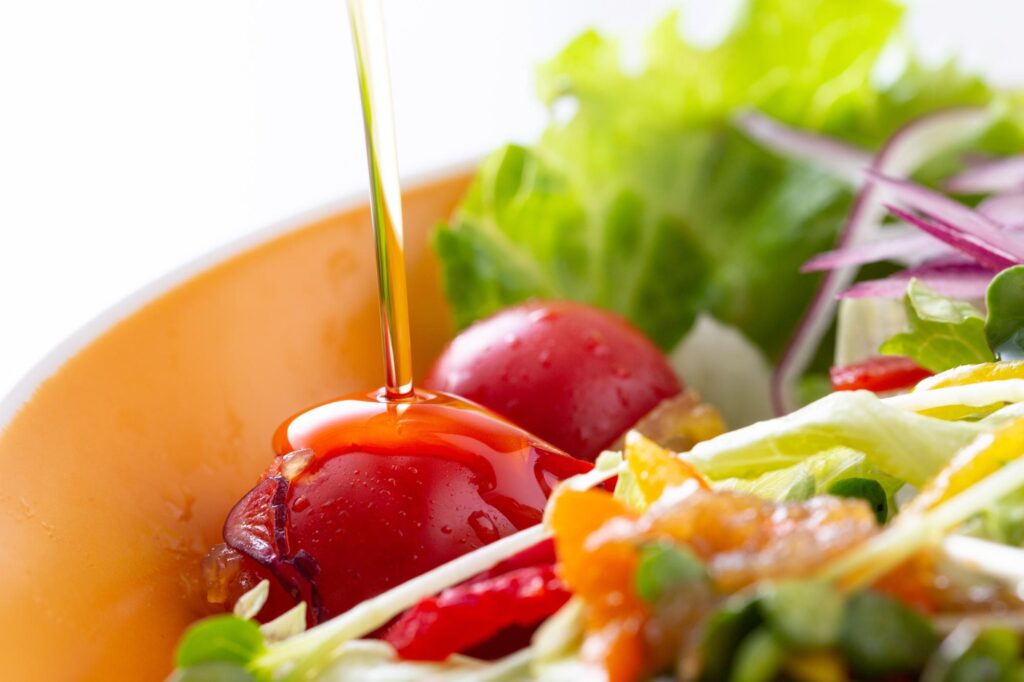 サラダにオリーブオイルをかける様子